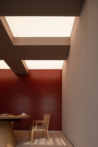 Cozy dining room with red walls, a wooden table, and two chairs, featuring a bowl and a cup on the table