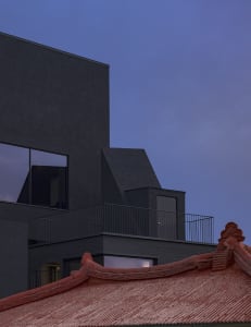 A modern Chinese-style building with a red roof and black walls, featuring symmetrical windows and a blend of traditional and contemporary architectural elements