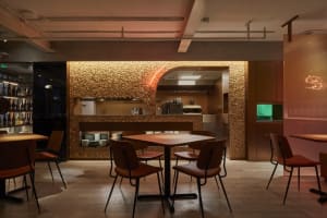 Warm and inviting restaurant interior with wooden floors and walls, featuring multiple tables and chairs in a cozy dining atmosphere