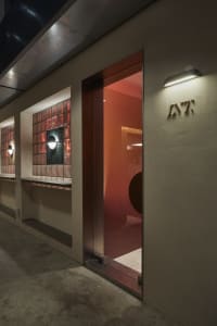 Narrow hallway with concrete walls, two doors, and a few windows, giving a modern and functional feel