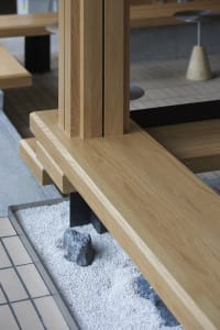 Indoor space with wooden floors and walls, featuring benches with rocks, a calm and inviting atmosphere