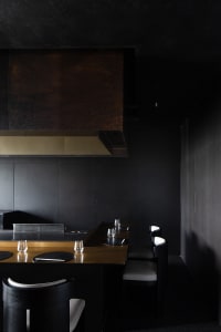 Modern kitchen with black walls, a countertop with wine glasses and knives, and a focus on functionality