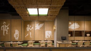 Dining area with a woven ceiling, chairs, and a dining table, surrounded by bottles and an inviting atmosphere