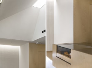 A living area with a large window and fireplace, featuring wooden walls and flooring, with a bright and cozy atmosphere
