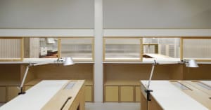 Two wooden desks with lamps and chairs in a well-organized office space