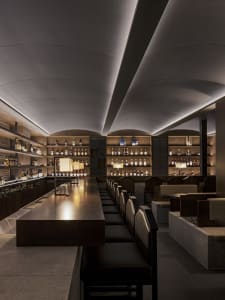 An inviting bar area with a long wooden counter, chairs, and bottles, creating a relaxed atmosphere