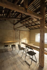 Open living space with wooden beams on the ceiling and walls, featuring a dining table and two chairs in a warm and inviting atmosphere
