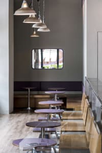 A purple-themed restaurant with round tables and chairs, creating a comfortable dining environment
