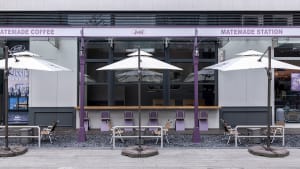 A restaurant dining area with tables, chairs, umbrellas, and potted plants, creating a warm and inviting atmosphere