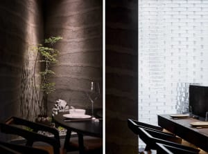 A cozy dining area with a wooden table and chairs, a potted plant, and a wine glass on a table, creating an inviting atmosphere for guests