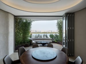 A cozy dining area with a wooden table surrounded by chairs, potted plants, and a bench, creating a warm and inviting atmosphere for meals and gatherings