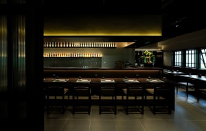 Dark and intimate restaurant with wooden elements, numerous dining tables, and chairs