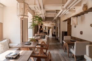 Modern restaurant interior with wooden floors and walls, featuring dining tables and chairs in a warm and inviting atmosphere