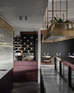 Elegant restaurant interior with a marble countertop, wine bottles, and comfortable seating for guests