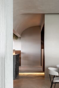 A modern hallway with a curved wall, two chairs, and a dining table, creating a unique and well-designed space