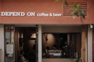 A casual coffee shop interior with natural light, patrons, and various objects such as cups, a vase, and a potted plant