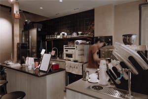A casual coffee shop interior with cups, bottles, and cakes on display, creating a welcoming atmosphere