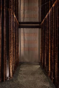 A warm and inviting hallway with bamboo walls, carpeted floor, and bamboo pillars