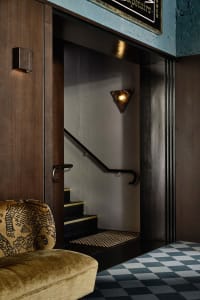 A hotel staircase with two sets of wooden stairs and black railings, set in an elegant and well-designed interior space