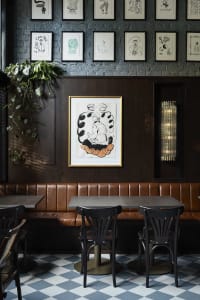 warm and inviting restaurant interior with wooden walls and tables, two dining tables with chairs, and potted plants