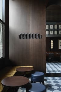 Warm and inviting restaurant interior with wooden walls and floors, featuring two dining tables, chairs, and benches, creating a cozy atmosphere