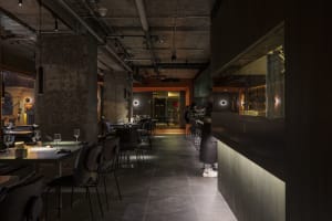 A modern restaurant with a large dining area featuring multiple tables and chairs, wine glasses, and an inviting atmosphere