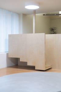 Office space with wooden walls, floors, and partitions, featuring modern furniture and a functional atmosphere