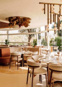 A spacious restaurant dining area with multiple tables and chairs, potted plants, and an inviting atmosphere