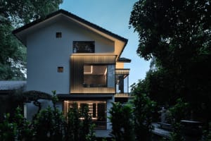 A large white house with multiple windows and doors, featuring a mix of concrete and wood materials, in a well-lit and spacious modern design