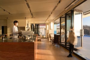 Casual restaurant interior with a counter, chairs, and a person standing near the counter