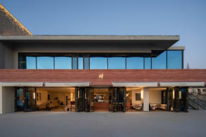 A wooden building with multiple windows, featuring comfortable seating areas with a potted plant and inviting atmosphere