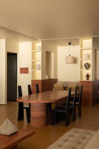 A warm and inviting dining area with a wooden table, black chairs, and decorative vases, perfect for meals and socializing