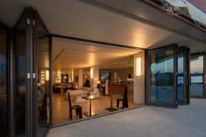Open living area with a modern aesthetic, featuring a seating area with a couch and chairs, a dining table, and a kitchen with a sink and refrigerator, surrounded by decorative elements and well-lit