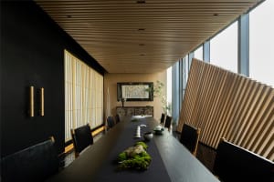 Elegant dining area with a long wooden table, chairs, vases, and well-lit space with a sophisticated ambiance