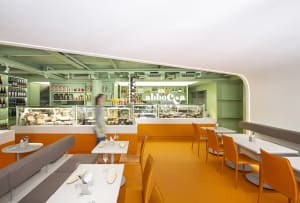 Cozy restaurant interior with orange accents, tables, chairs, and wine glasses, creating an inviting atmosphere