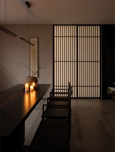 A dining area with a black table and chairs, candles, and vertical blinds, conveying elegance and sophistication