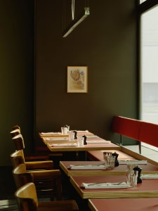 An inviting restaurant with several dining tables and chairs, set with place settings and ready for customers