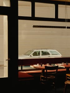 Warm and inviting dining space with a red table, comfortable seating, and a view of a car outside through a window