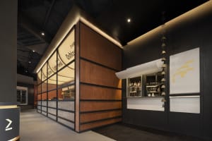 A cozy restaurant bar with a wooden counter, bottles, and cups, inviting atmosphere