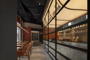 Modern restaurant with a clean and minimalist design, featuring black and white tiles, chairs, and tables