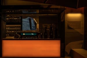 A casual dining environment with an orange bar counter, cups, and a TV mounted above, in a restaurant or cafe setting