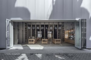 A cozy coffee shop interior with a large display window showcasing cups, bowls, and bottles, surrounded by chairs for customers to sit and enjoy their beverages
