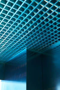 Modern room with a large blue wall featuring a checkered pattern, metal walls, and two doors, creating a stylish and sophisticated atmosphere