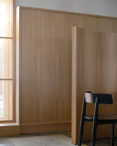 Empty dining room with wooden walls and floors, featuring a dining table and two chairs in a calm and inviting atmosphere