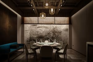 Dining area with a round table, stone walls, and fine china and wine glasses