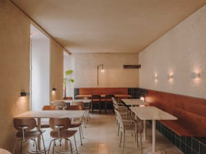 Modern restaurant interior with multiple tables and chairs, white and brown walls, and well-designed lighting