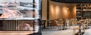 A restaurant interior with wooden walls and floors, featuring various chairs and a warm atmosphere