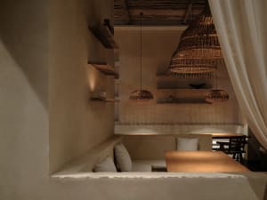 Dining area with a wooden table and chairs, two couches, and a warm ambiance created by dim lighting and wood and stone elements