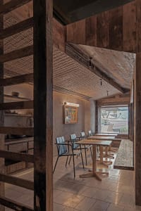 Open living space with a dining table, chairs, kitchen area, and natural light from a window, featuring a modern and inviting atmosphere