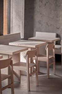 Empty restaurant interior with modern wooden tables and chairs, clean and inviting atmosphere, warm and cozy feel, well-designed lighting